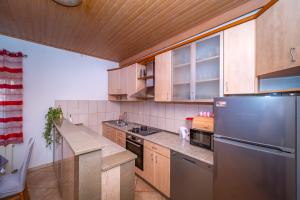 a kitchen with wooden cabinets and a stainless steel refrigerator at Spacious apartment 50 m from the beach in Postira +20 photos