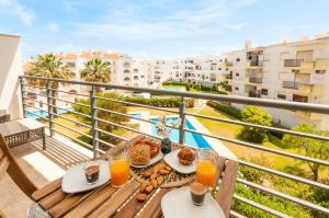 a table with food and orange juice on a balcony at Almond Apartment by OCvillas in Vale de Pedras