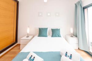 a bedroom with a white bed with blue pillows at Almond Apartment by OCvillas in Vale de Pedras +24 photos
