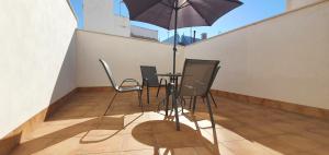 balkon ze stołem, krzesłami i parasolem w obiekcie JOSE APARTAMENTo w mieście San Jose de la Rinconada