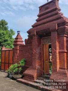 GRHA PAWITRA TROWULAN في Trowulan: مبنى من الطوب الأحمر مع باب خشبي