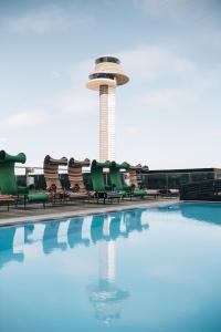 a pool with chairs and a control tower in the background at Clarion Hotel Arlanda Airport Terminal in Arlanda