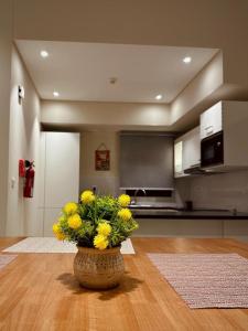 um vaso com flores amarelas sentado numa mesa numa cozinha em one bedroom villa em Salalah