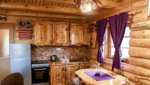 a kitchen with wooden cabinets and a table in a cabin at Ivana in Kupres