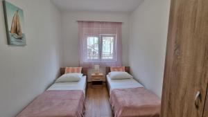 two beds in a small room with a window at Apartment Gogo Duce in Duće