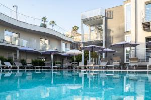 a pool with chairs and umbrellas in a hotel at Hotel Malavoglia in Acitrezza