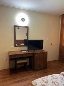 Cette chambre comprend un bureau avec une télévision et un miroir. dans l'établissement Хотел Ажур, à Kotel