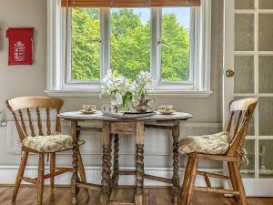 Hollesley的住宿－夜鶯鄉村別墅，一张桌子,两把椅子和花瓶