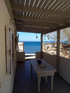 un patio con mesa y vistas al océano en Spilios House en Apollon