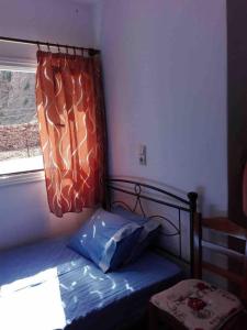 a small bedroom with a bed with a window at Spilios House in Apollon