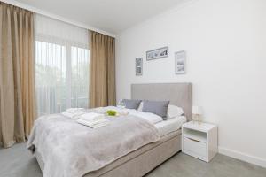 a white bedroom with a large bed and a window at Wellness Resort & SPA Dziwnów Apartments with Parking by Renters in Dziwnów