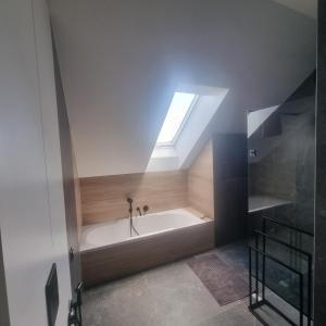 a bathroom with a bath tub with a skylight at Premium House Osztynek in Olsztynek