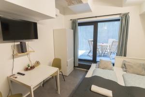 een woonkamer met een bank en een tafel met een televisie bij Peaceful Basement Apartment with Terrace & free GYM in Boedapest