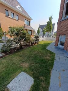 a yard in front of a house with a sidewalk at Le White Garden in De Panne