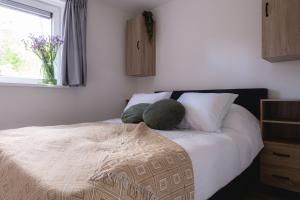 een slaapkamer met een bed met een kussen en een raam bij Luxe Vakantiehuis Koekoek Veluwe in Nunspeet