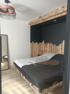 1 dormitorio con 1 cama con cabecero de madera en Le hangar de mamie, en La Charrière