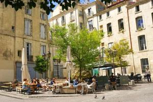 un groupe de personnes assises à des tables avec des parasols dans l'établissement *Appart 2 chambres, Hypercentre, Emplacement N°1*, à Montpellier