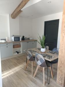 comedor con mesa y sillas y cocina en Le hangar de mamie, en La Charrière