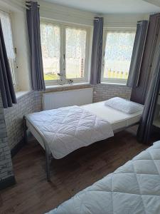 a bedroom with two beds and two windows at Le White Garden in De Panne