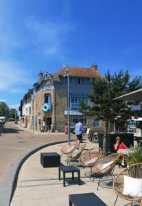 a group of chairs and tables on a street with a building at LA MAISON BLEUE in Quiberon