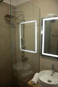 a bathroom with a sink and a shower with a mirror at Wave Beachfront Apartments in Durrës