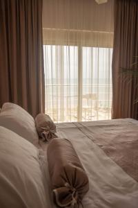a bedroom with a bed with pillows and a window at Wave Beachfront Apartments in Durrës