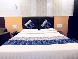 Cama grande con sábanas y almohadas azules y blancas en Kaveri Palace, en Mysore