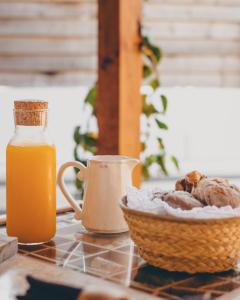 a bowl of bread and a jug of orange juice and a basket of oranges at Casa do Lado in Vila Nova de Milfontes