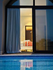 Hawana Lagoon Private villa with private pool في صلالة: مسبح مطل على غرفة نوم من خلال نافذة