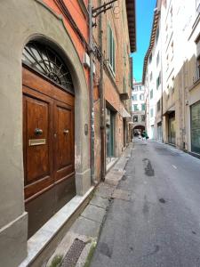 eine leere Straße mit einer Holztür an einem Gebäude in der Unterkunft Suite Heart in Pisa