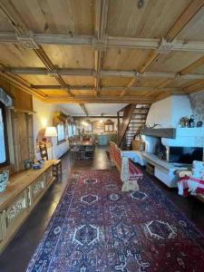 een grote woonkamer met een houten plafond en een groot tapijt bij Casa incantevole di Montagna con vista mozzafiato in Roana