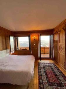 een slaapkamer met een bed, een tapijt en ramen bij Casa incantevole di Montagna con vista mozzafiato in Roana