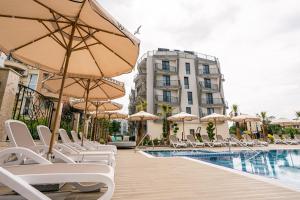 a pool with chairs and umbrellas next to a building at хотел ADDRESS in Ravda