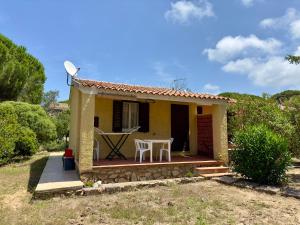 una pequeña casa amarilla con una mesa en el porche en Tramonto, Rena Majore, en Rena Majore