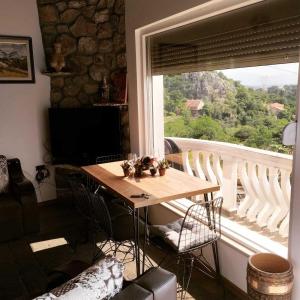 a table and chairs in a room with a large window at WOODSTONE APARTMAN in Podgorica