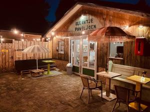 un restaurante con mesa, sillas y sombrilla en Minicamping Kleintje Zandpol, 