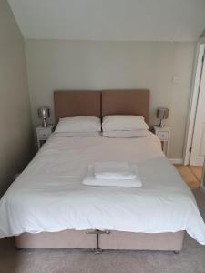 a large white bed with white sheets and pillows at The Ship Inn in Truro
