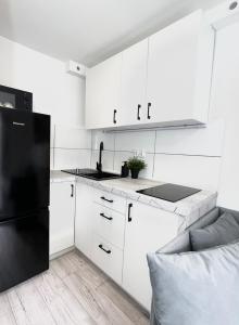 cocina con armarios blancos y nevera negra en Apartament Goplańska FREE PARKING, en Poznan