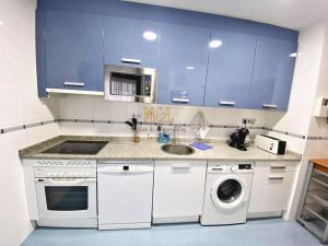 une cuisine avec des armoires bleues et un lave-linge dans l'établissement Viyago, à Oviedo
