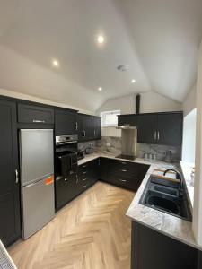 a kitchen with black cabinets and a stainless steel refrigerator at The Mount in Swansea