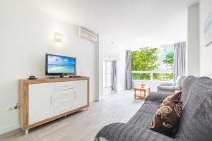 Gemelos 22 Resort Apartment 3-1C Levante Beach في بنيدورم: غرفة معيشة مع أريكة وتلفزيون بشاشة مسطحة