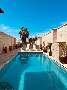 a swimming pool with chairs next to a building at Narcisa Farmhouse B&B in Nadur