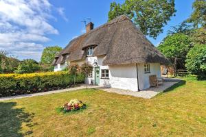una casa con tetto in paglia e cortile. di Finest Retreats - Pemberley Cottage 