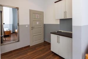 cocina con armarios blancos, espejo y puerta en Motel Kobilj, en Banja Luka