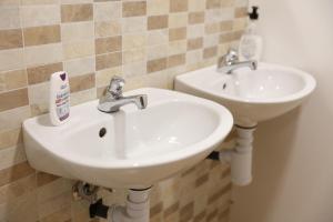 2 lavabos blancos en un baño con paredes de azulejos en ALBERGUE EL CAMINANTE en Portomarin