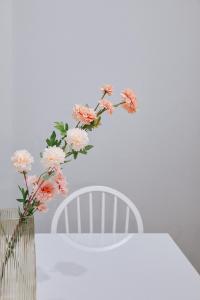 a vase of flowers sitting on a table with a white chair at C Apartments in Melissátika