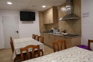 Zimmer mit 2 Tischen und einer Küche mit einem TV in der Unterkunft ALBERGUE EL CAMINANTE in Portomarin