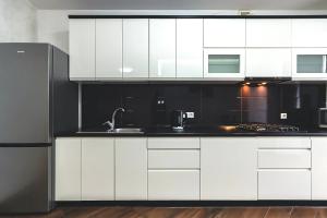 eine Küche mit weißen Schränken und einem schwarzen Kühlschrank in der Unterkunft Cozy apartment on Belvedere in Iwano-Frankiwsk