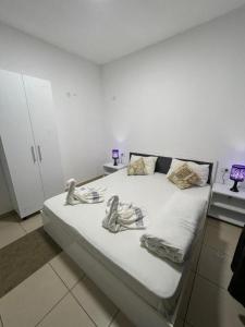um quarto com uma cama com lençóis brancos e almofadas em Hostel Tripoli Palace em Bucareste