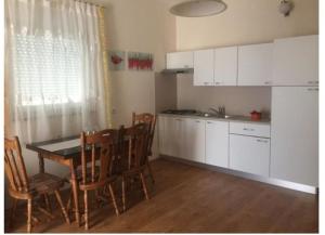 kuchnia ze stołem, krzesłami i białymi szafkami w obiekcie Apartment Olives w mieście Zadar